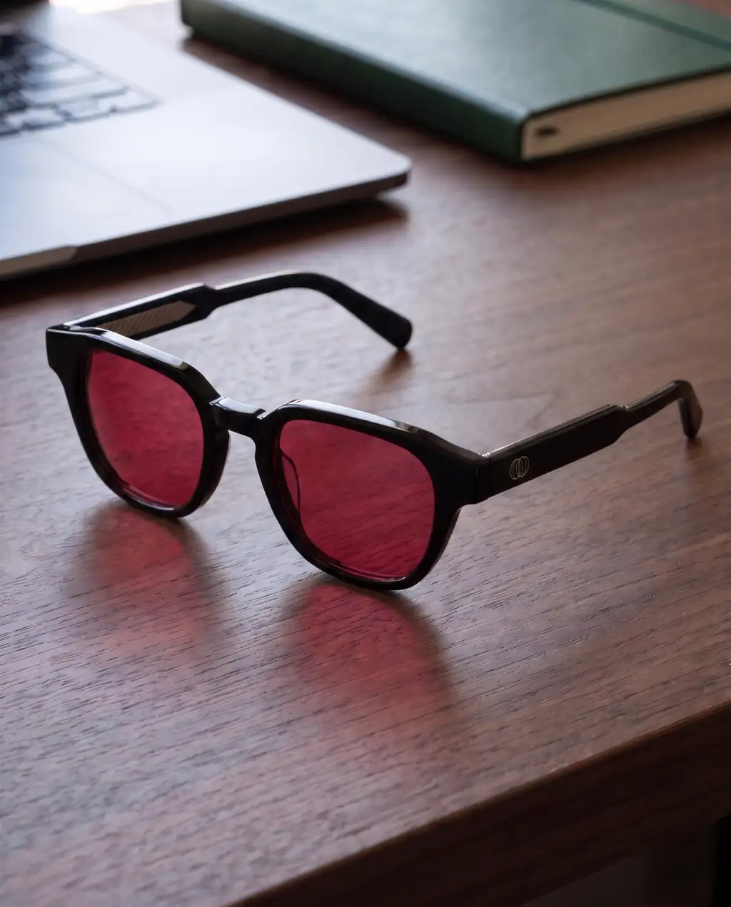 Origo Red lens, black frame — on a desk