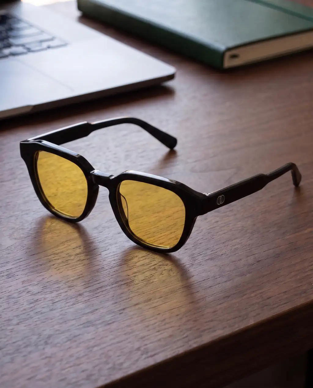 Origo Yellow lens, black frame — on a desk